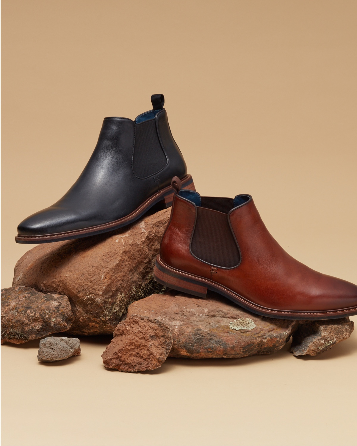 black boot and brown boot on rocks
